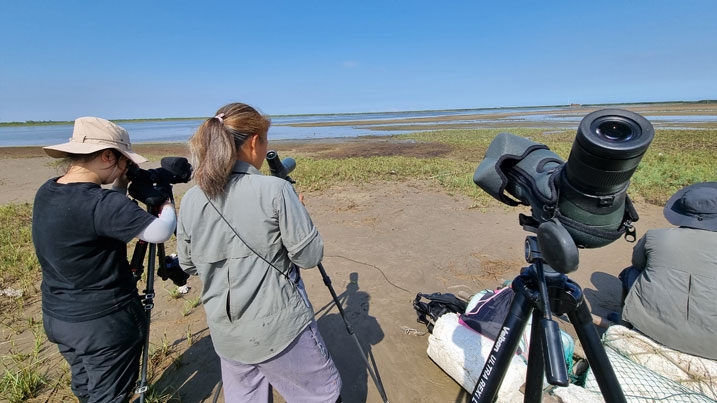 Two women looking through scopes onto the mudflats in Eastern China