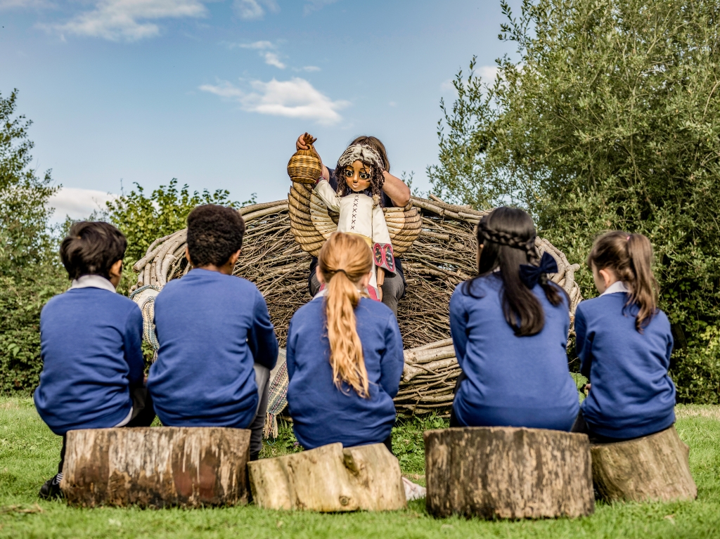 Group of school children listening to a puppet show with Generation Wild's Ava character.