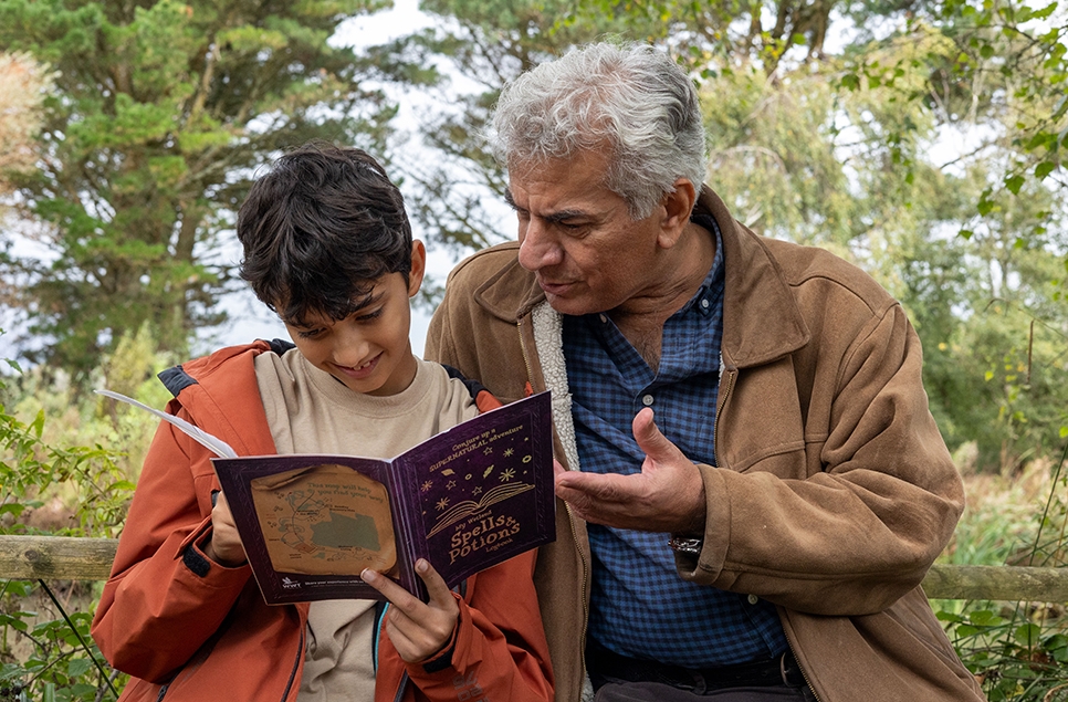 A child and adult looking through a spells and potions logbook