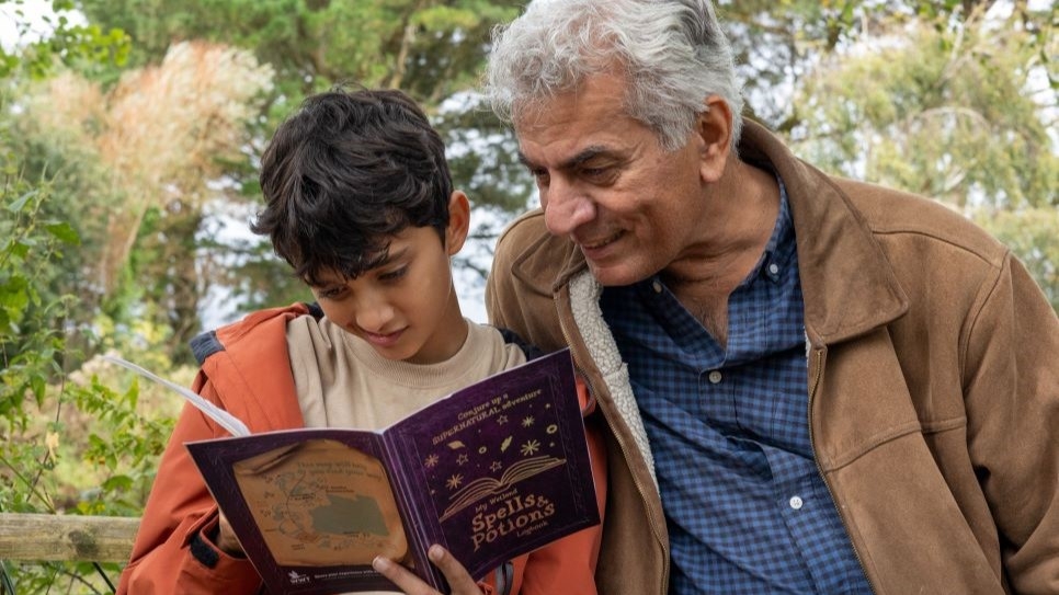 Child and grandfather reading the 'Spells and Potions' logbook