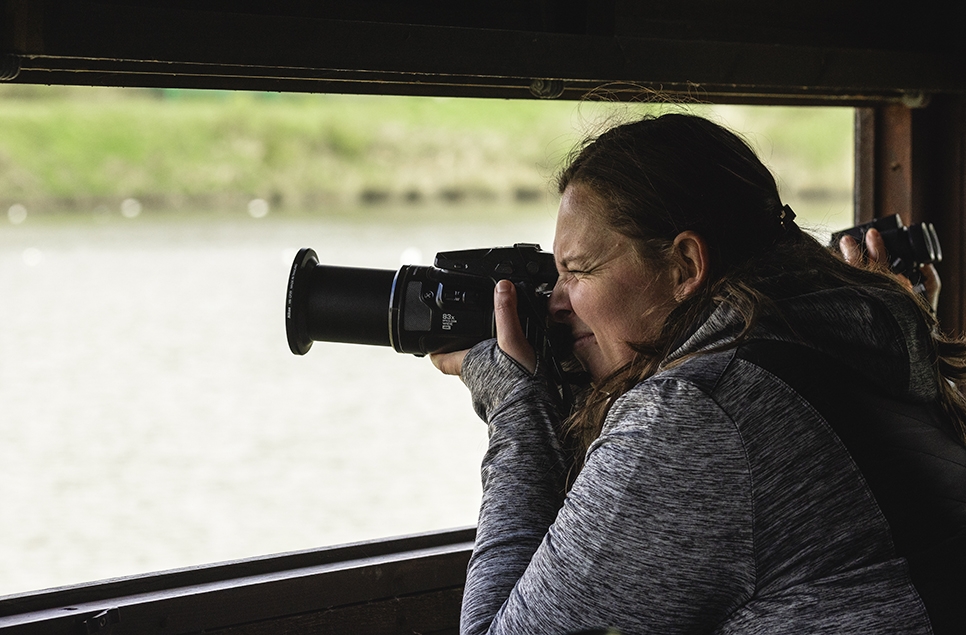 Deborah looking through the lens of her camera in a hide 