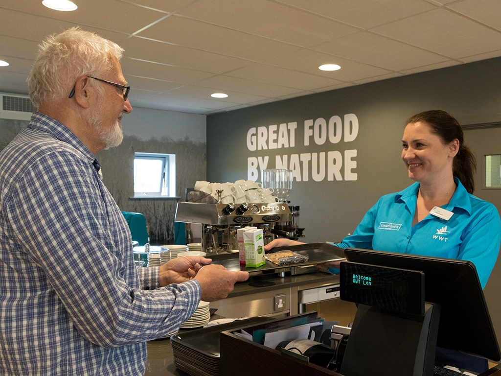 A member of staff hands a customer a tray of drinks