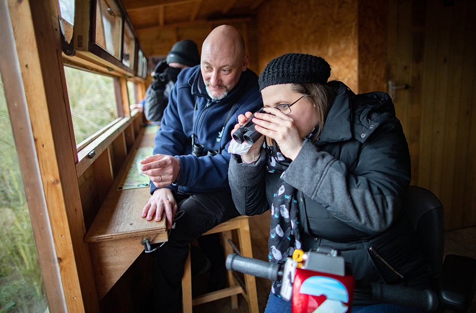 John Gowland in a hide with a visitor pointing out a species