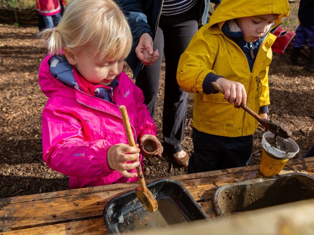 Two children playing at a mud kitchen.