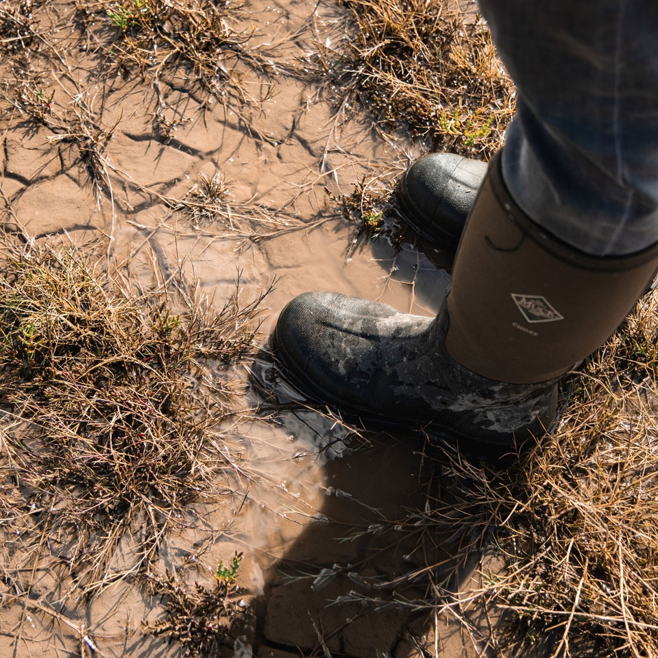 Person in wellington boots exploring a UK saltmarsh at high tide